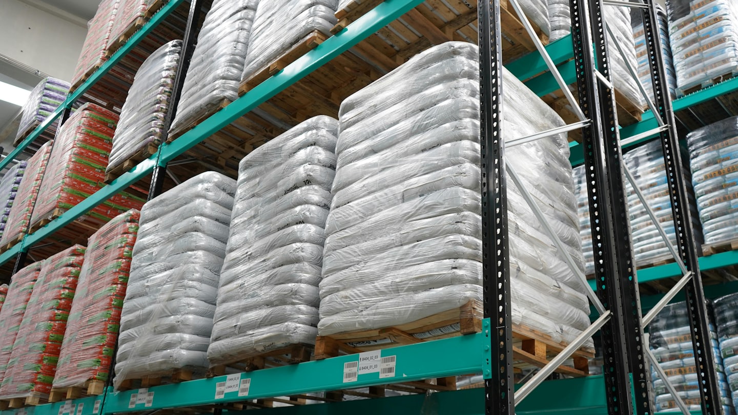 Industrial warehouse filled with shelved goods on pallets.